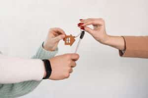 Arms taking keys and house keychain. Couple receiving house key from real estate agent. Key in hands