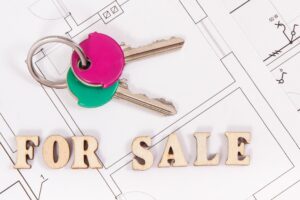 Home keys with inscription for sale on housing plan, concept of selling or buying house